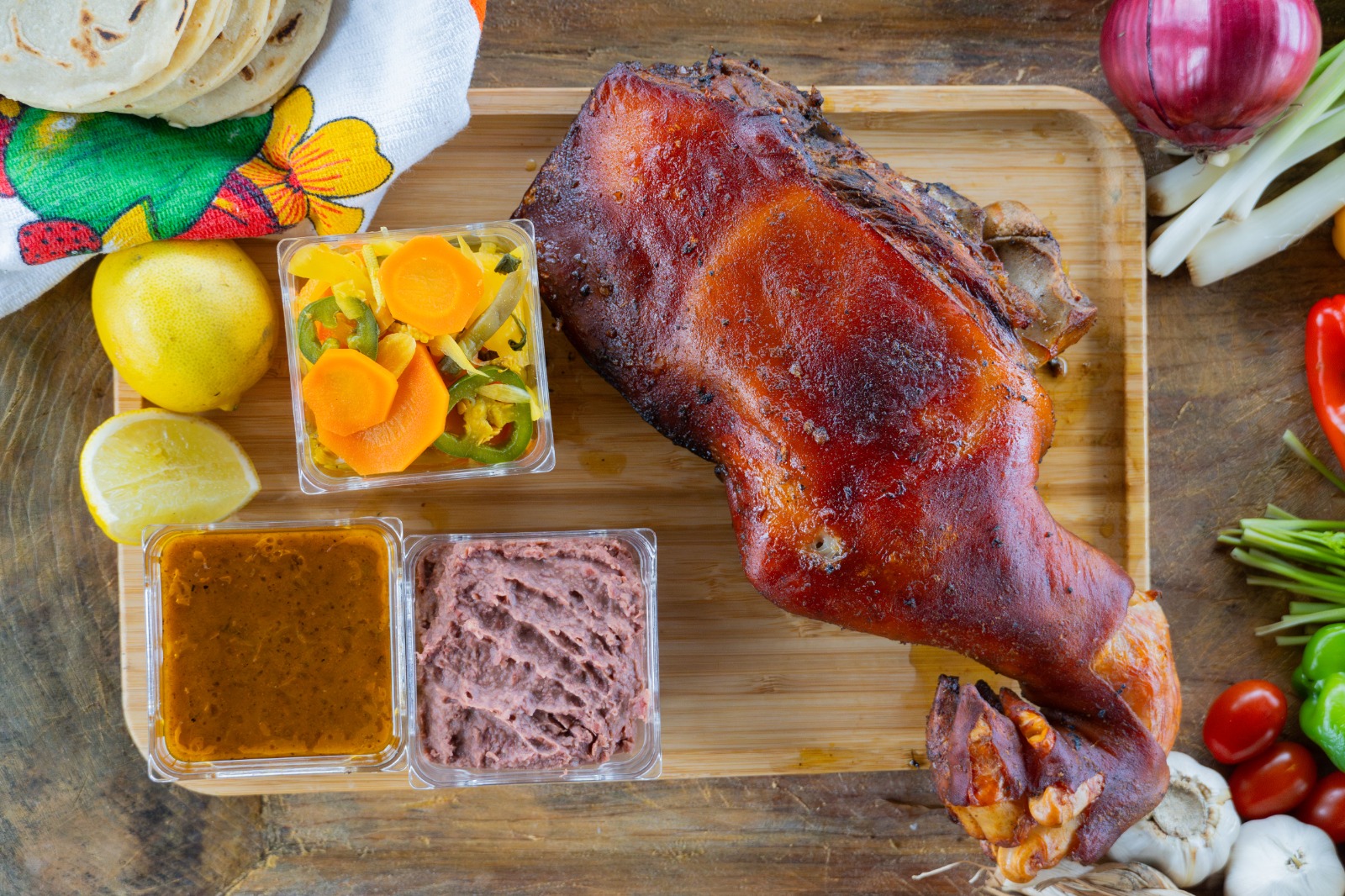 Cerdito horneado sobre tabla con frijoles, encurtido y tortillas