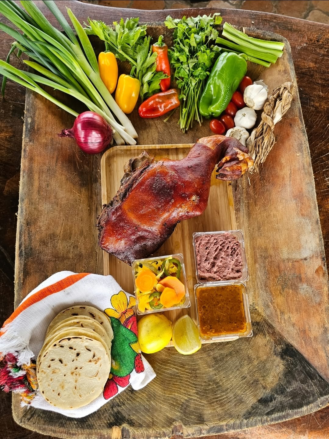Ingredientes frescos y cerdito horneado sobre mesa de madera